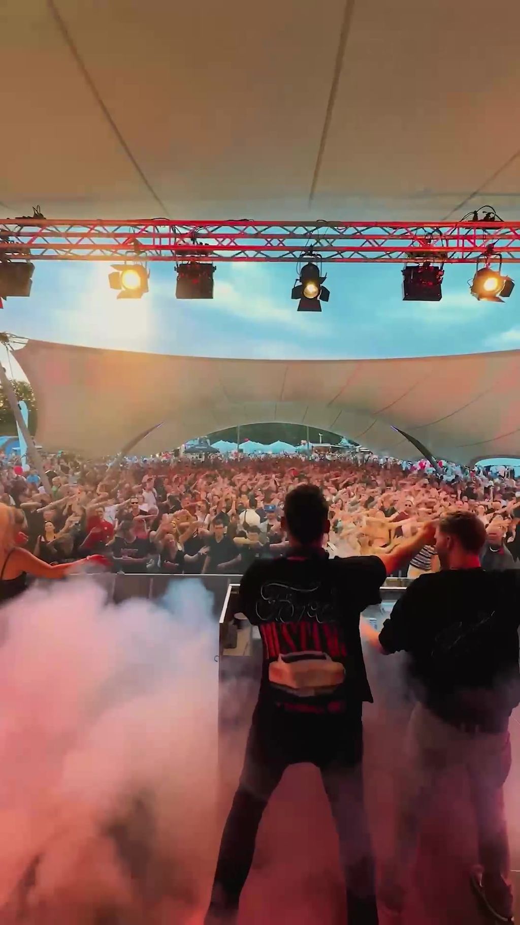 Topmodelz on stage facing a large crowd under a festival tent roof